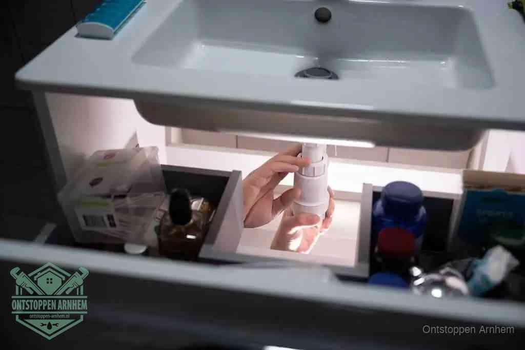 Een pompfles met zeep boven een wastafel, de heet water en afwasmiddel-methode om een vetprop in de afvoer los te maken in Arnhem
