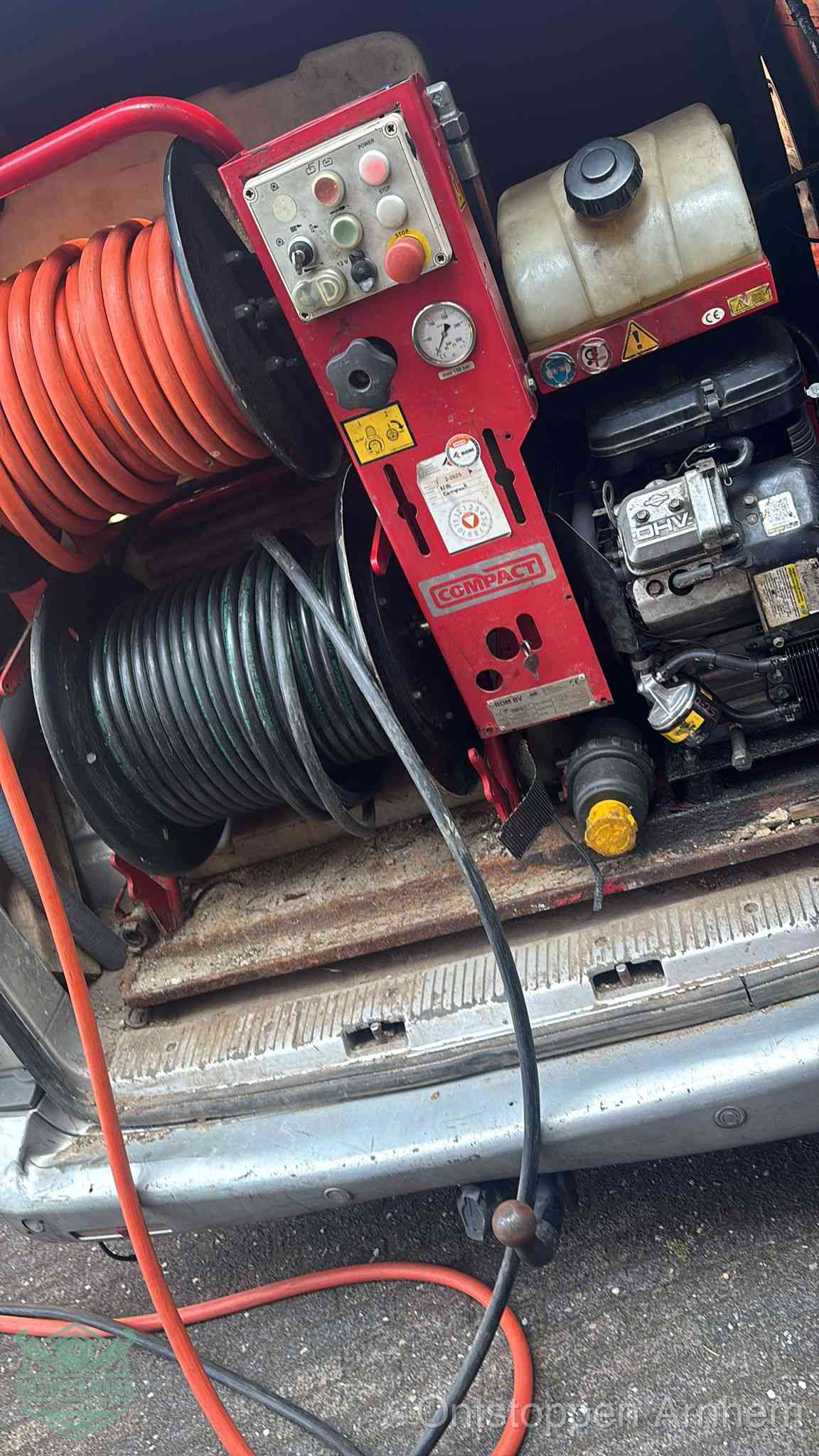 Een rood hogedruk-rioolreinigingstoestel in de laadbak van de bedrijfsbus, apparatuur voor een hardnekkige afvoerverstopping in Arnhem