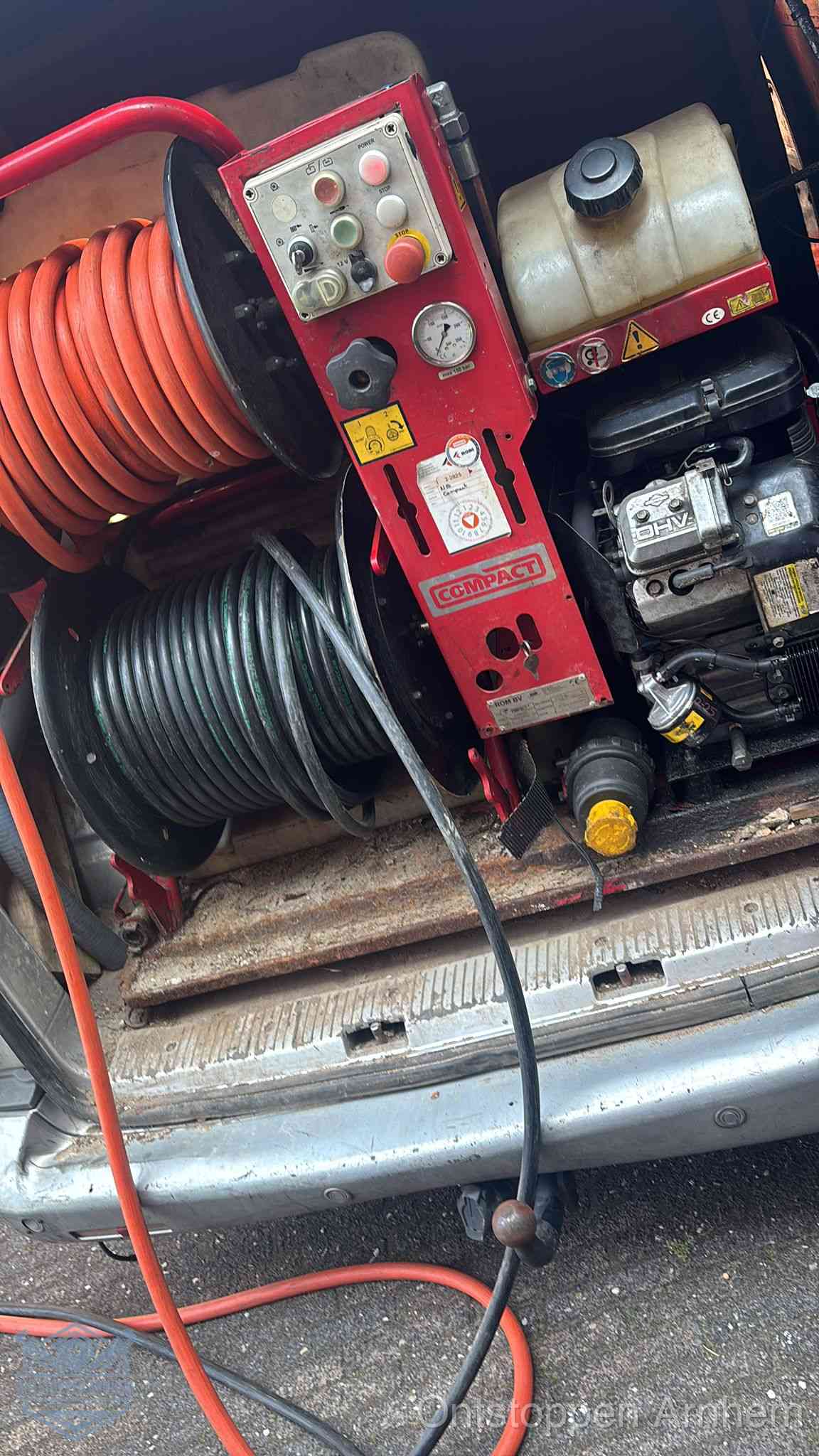 Een rood hogedruk-rioolreinigingstoestel met slangen in de laadbak van de bedrijfsbus, apparatuur voor een hardnekkige wc-verstopping in Arnhem
