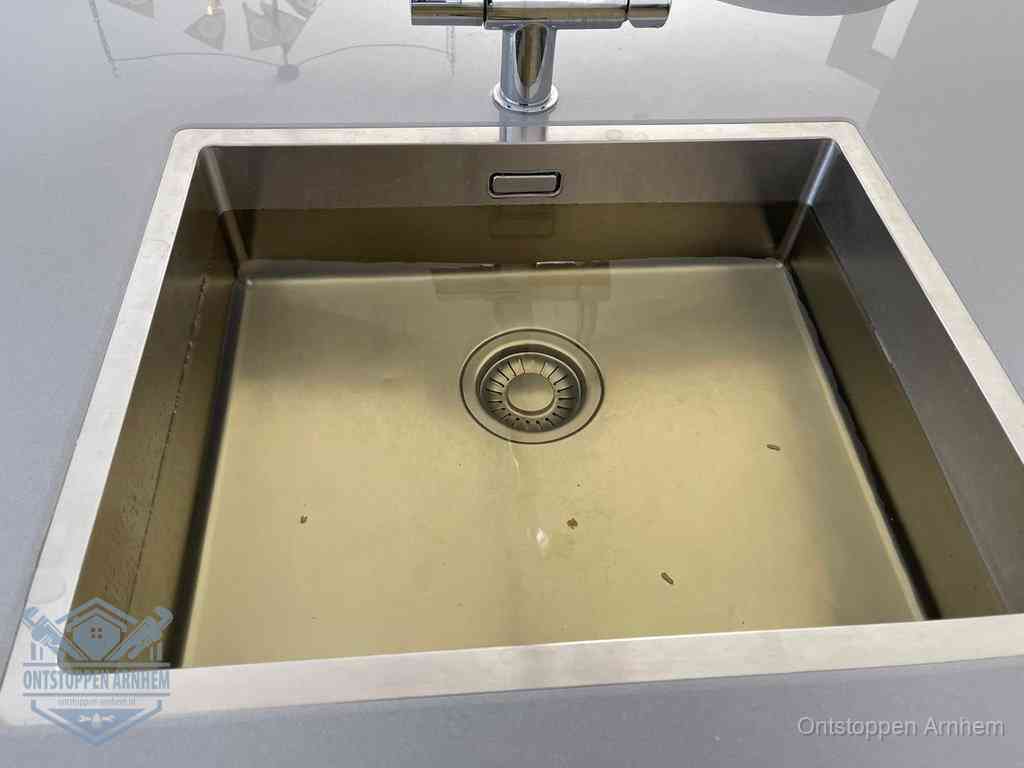 Stilstaand water in een rvs spoelbak dat niet wegloopt, een duidelijk signaal van een gootsteenverstopping in Arnhem