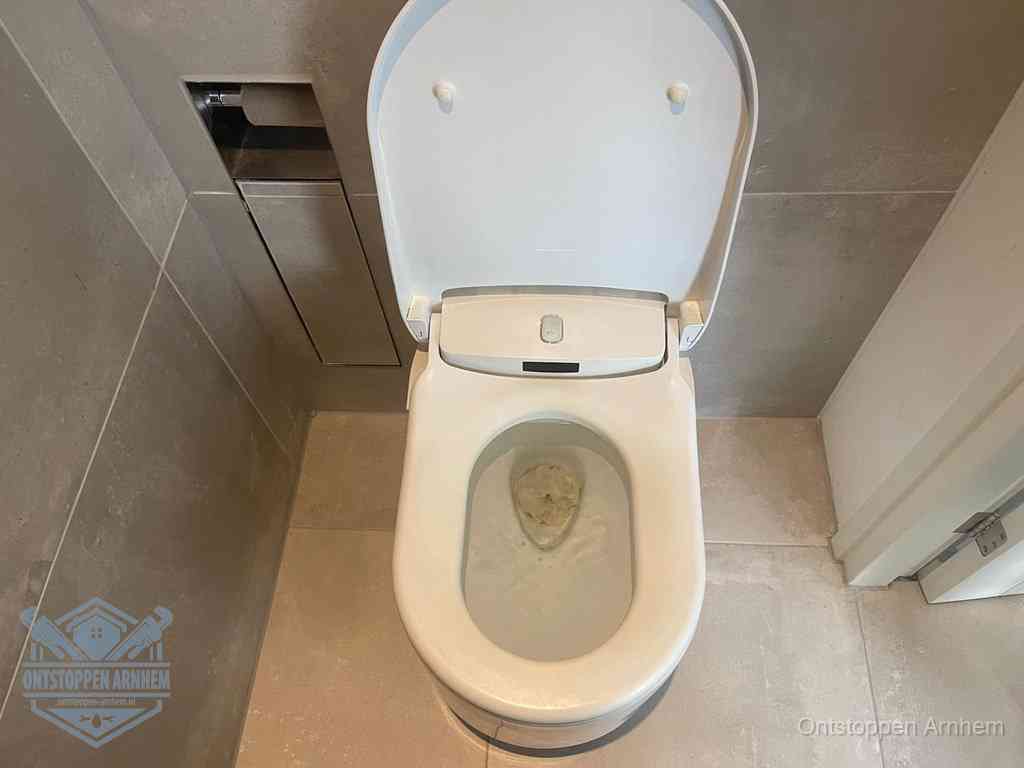 Een wit hangtoilet waarin een prop wc-papier op het water blijft drijven, een duidelijk signaal van een verstopte wc in Arnhem