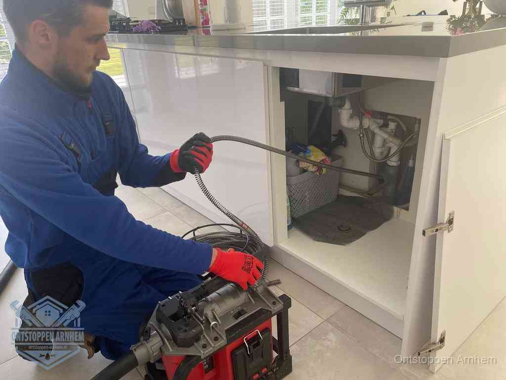Een monteur reinigt de keukenafvoer grondig met een veermachine om terugkerende gootsteenverstoppingen te voorkomen in Arnhem