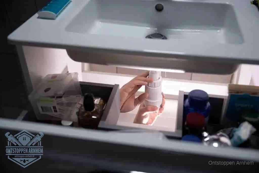Een pompfles met zeep boven een wastafel in de toiletruimte, de warm water en afwasmiddel-methode om de wc te ontstoppen in Arnhem