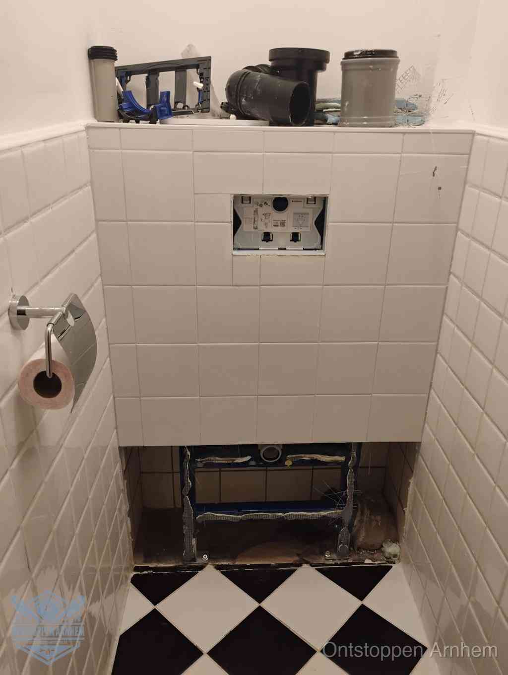 Een toiletruimte waar het hangtoilet en de inbouwreservoir-onderdelen zijn vrijgelegd voor onderhoud, periodiek nazicht voorkomt een wc-verstopping in Arnhem