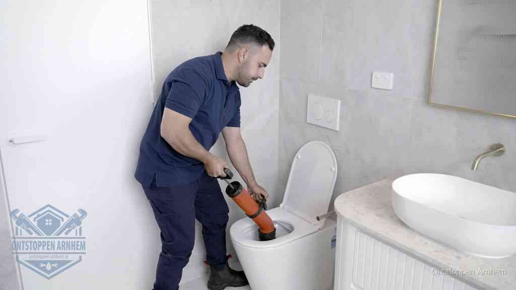 Een monteur gebruikt een handmatige perspomp (toiletontstopper) op een wandcloset tijdens het professioneel wc ontstoppen in Arnhem